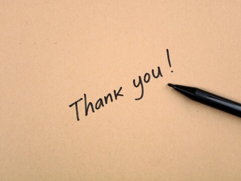 Handwritten Thank You message with black marker pen on rustic brown craft paper texture background. Concept of gratitude, appreciation, note, customer service, and feedback