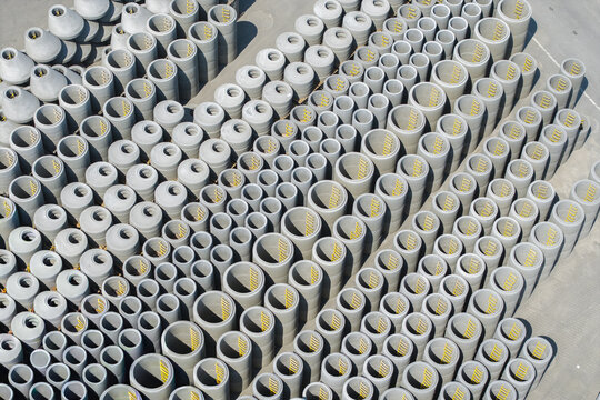 Aerial view of numerous concrete manhole sections and pipes arranged in rows at a manufacturing facility in Poland.