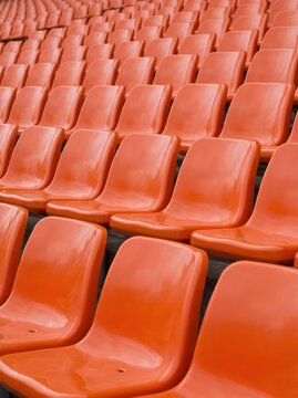 Empty stadium seats in vibrant orange rows awaiting spectators for an event.