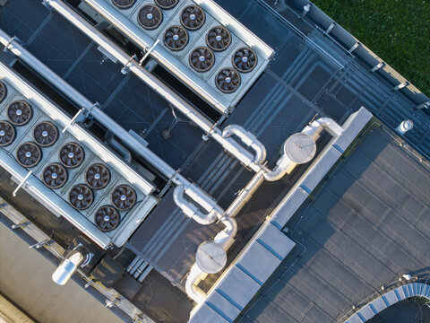 Aerial view of an AI data center cooling system featuring rows of industrial fans and metallic piping on a flat rooftop in Krakow, Lesser Poland Voivode, Poland.
