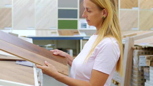 Woman Comparing Laminate Flooring Panels in Home Improvement Store