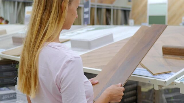 Woman Inspecting Laminate Flooring Sample in Home Improvement Store