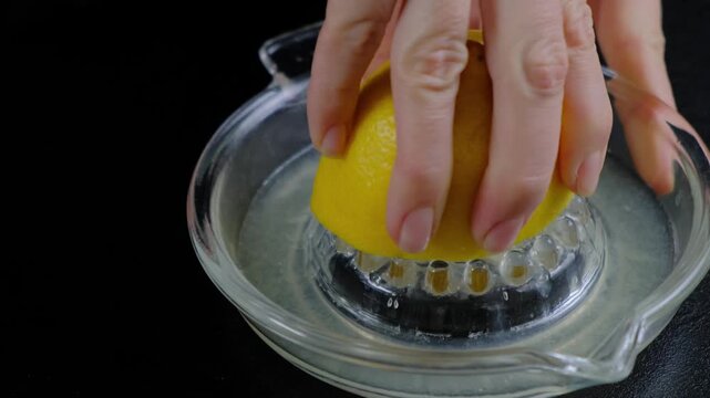Close-up of hands squeezing a lemon over a dental retainer in a dish of water, cleaning it at Cooking location.