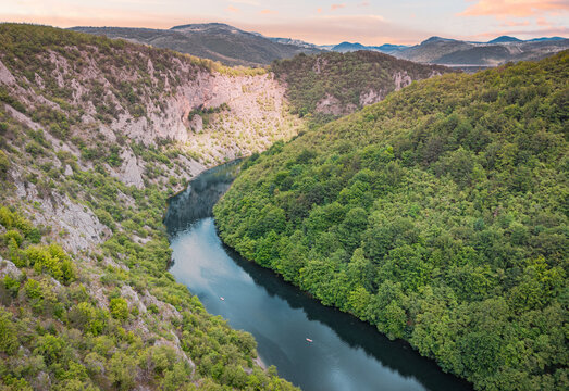 Aerial drone view of kayakers paddling through a lush green river canyon. Adventure concept.