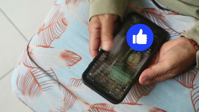 An elderly person holding a smartphone and interacting with social media content.