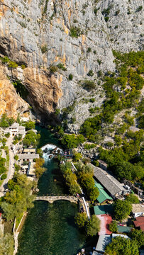 Aerial view of the historic Blagaj Tekke monastery nestled at the base of a massive limestone cliff beside the turquoise Buna River in Blagaj, Federation of Bosnia, Bosnia and Herzegovina.