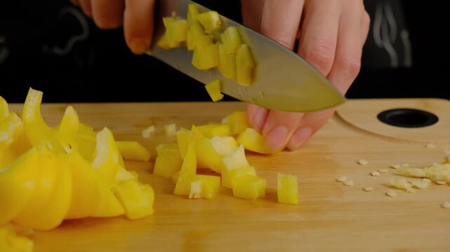 Close-up of hands slicing fresh mango on wooden board with chef's knife during food preparation in Cooking kitchen, daytime.