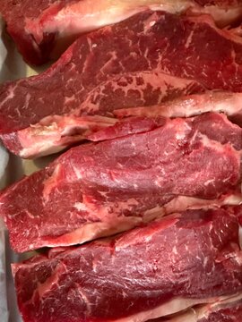 Fresh raw beef steaks displaying rich marbling, offering a close up texture of uncooked red meat, emphasizing protein, carnivore diet, and food preparation