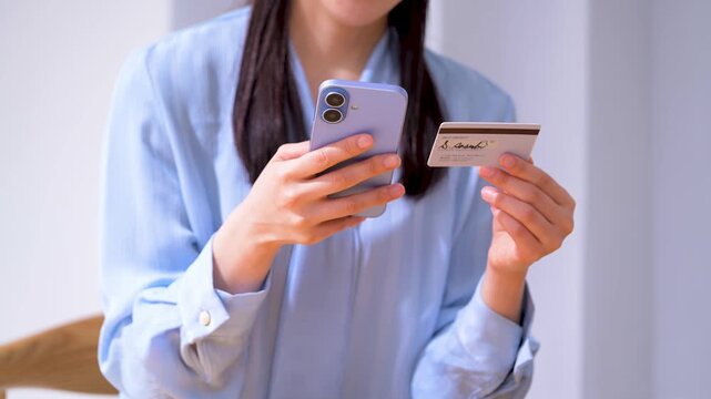 クレジットカードを見ながらスマホを操作する女性