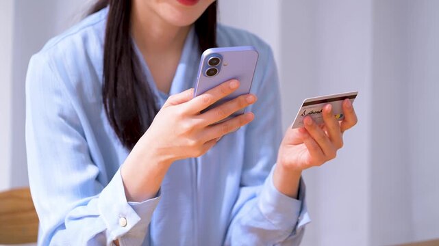 クレジットカードを見ながらスマホを操作する女性