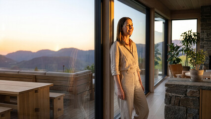 Obraz premium Woman standing looking at mountain sunset view in modern room with concrete wall