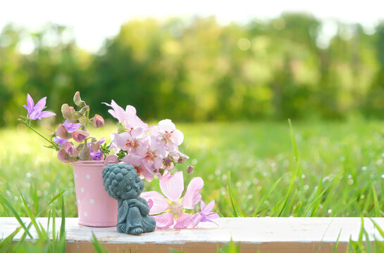 beautiful miniature asian style girl figurine and flowers close up outdoor, natural background. landscape with cute little girl Buddhist monk figurine in garden. symbol of meditation, yoga. copy space