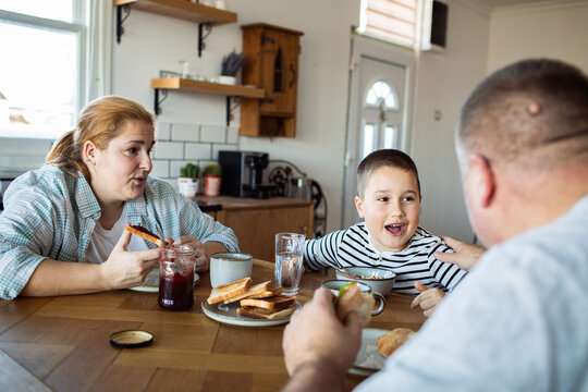 Parents and child eating breakfast together at home kitchen