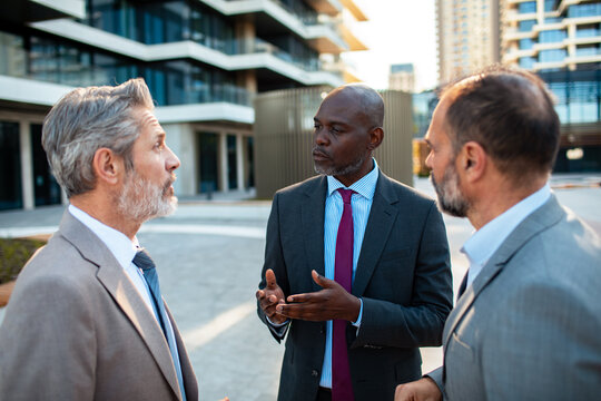 Three business executives discussing strategy outside city office