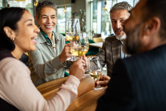 Happy colleagues toasting white wine at restaurant