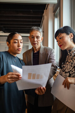 Coworkers reviewing charts together in an office