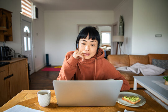 Woman working on laptop at home kitchen table