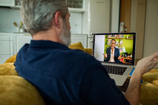 Mature man video chatting with consultant at home