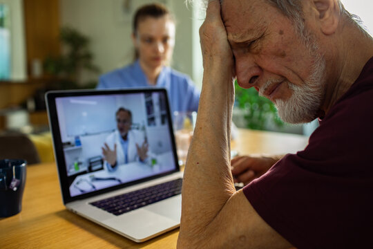 Senior man with headache during telehealth consultation at home