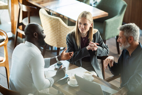 Three colleagues discussing project in coffee shop