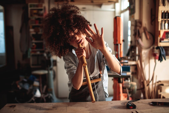 Person inspecting wooden dowel in home workshop