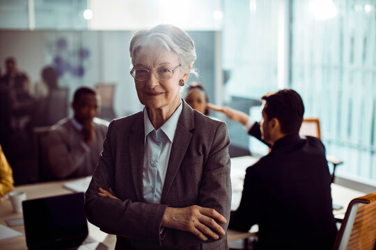 Confident senior businesswoman leading team in modern office