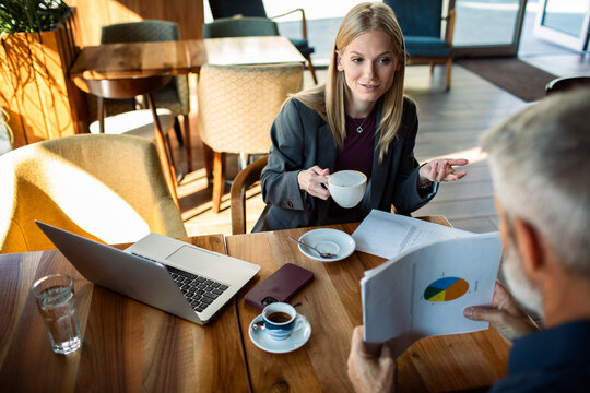 Business colleagues discussing charts over coffee in a cafe
