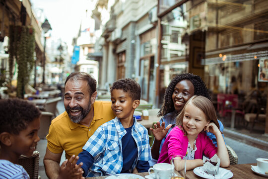 Happy family with kids at outdoor cafe in city
