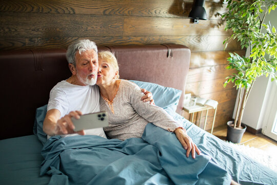 Senior couple taking a selfie in bed at home