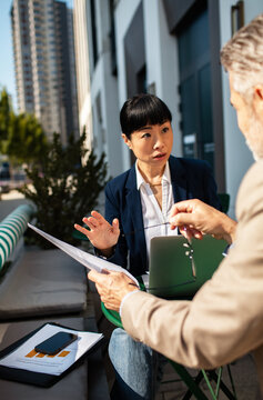 Business colleagues discussing documents at outdoor cafe in city