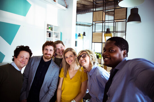 Diverse coworkers taking selfie in modern office