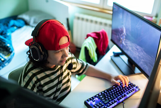 Teen gamer with headset playing pc game in bedroom
