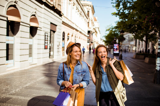 Two happy women shopping on city street