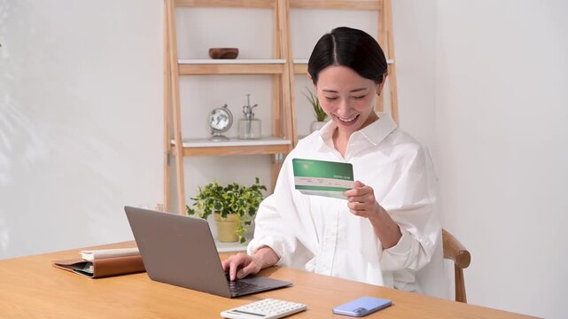 通帳を見ながらパソコン操作をする女性