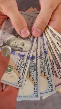 Vertical video. Woman Taking United States Dollar Banknotes One by One From a Man Hand Until No Cash Remains, Top Down View, Financial Loss, Debt Repayment