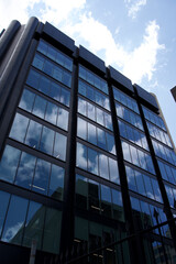 Obraz premium Tall Modern Glass Building Reflecting Sky and Clouds – Building, Modern, Architecture, Glass, Reflection, Sky, Cloud, Urban, Structure, Design, Contemporary 