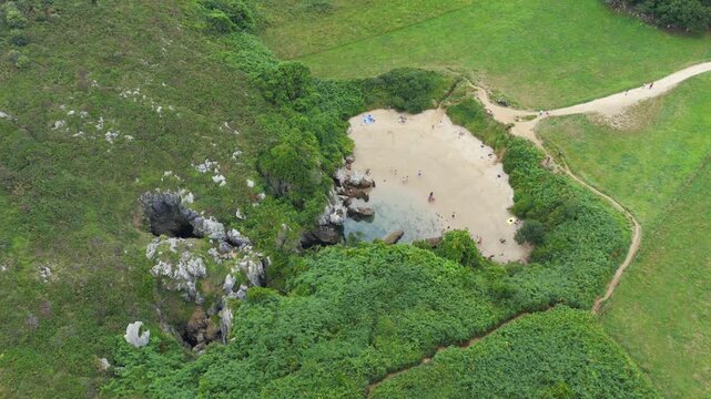 Aerial View of the Unique Inland Tidal Beach of Playa de Gulpiyuri Surrounded by Green Cliffs and Meadows in Asturias, Northern Spain
