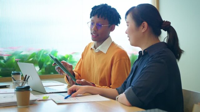 Diverse business colleagues discussing financial data and roadmap strategy on tablet computer in modern office	