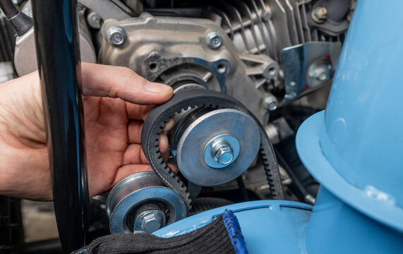 Man installs a snowblower auger drive belt. Equipment repair and maintenance.