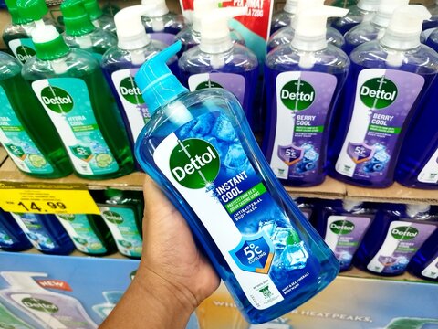 KUALA TERENGGANU, MALAYSIA- AUGUST 06. 2026: Person holding a blue bottle of Dettol Instant Cool Antibacterial Body Wash with organized retail supermarket shelf displays in the background.