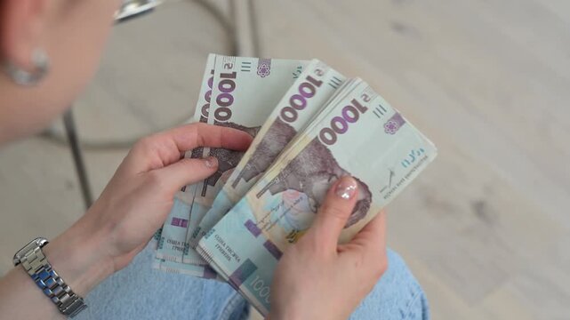 Woman hands counting Ukrainian hryvnia banknotes, 1000 uah bills money close up.