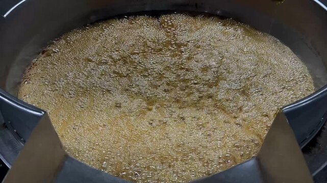Caramel sauce being continuously mixed in an industrial steam-heated kettle during food manufacturing operations. Large-scale cooking process supporting product consistency, texture control, and comme