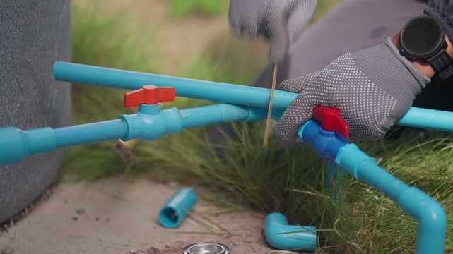 Technician works on household water pipes and valves during routine maintenance, illustrating plumbing repair, water distribution, pipe fitting, home improvement, and utility service.