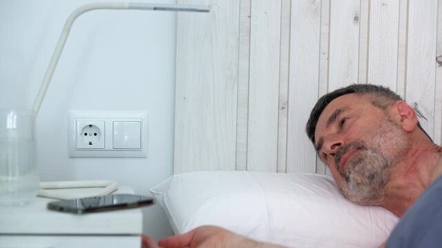 Mature man unplugging charger before going to sleep