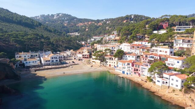 Aerial view of the turquoise waters and white houses of Sa Tuna cove nestled among pine-covered hills in Begur, Catalunya, Spain.