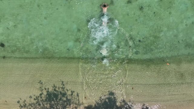 Aerial view of the clear turquoise waters and sandy shoreline of Koh Madsum, with tree shadows cast on the beach in Koh Samui, Chang Wat Surat Thani, Thailand.