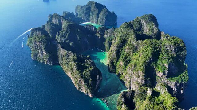 Aerial view of Phi Phi Islands with lush green limestone cliffs surrounded by turquoise water and boats in Mueang Krabi District, Krabi, Thailand.