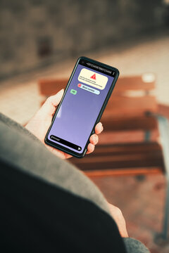 Woman holding smartphone with suspected scam call warning and block number option. Phone scams, cybersecurity, spam protection, and online safety awareness.