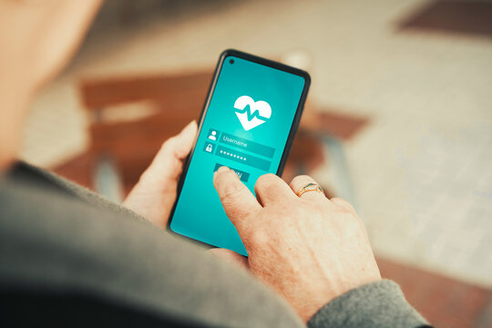 Mature woman logging into health tracking app with heartbeat icon on smartphone. Telehealth, fitness tracking, medical apps, and digital health management.