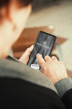 Mature woman viewing money received confirmation notification on smartphone. Mobile banking, digital payments, and online money transfers concepts.